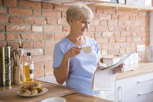 活力老妇人在厨房看报纸表面咖啡杯站