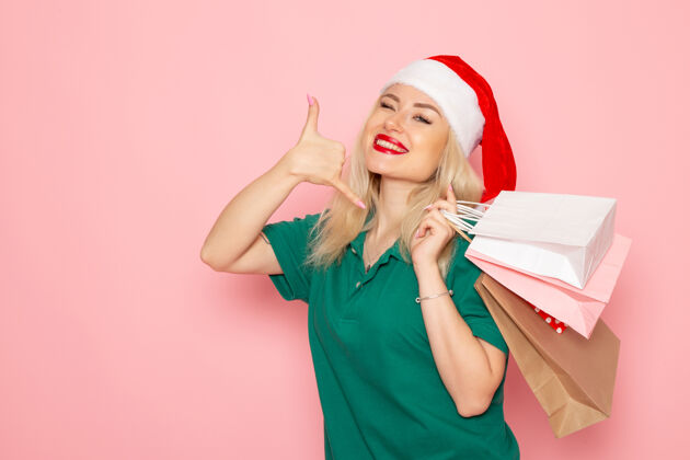 肖像正面图年轻女性拿着圣诞礼物在粉红色墙上包圣诞照片新年假期模型包装风景成人