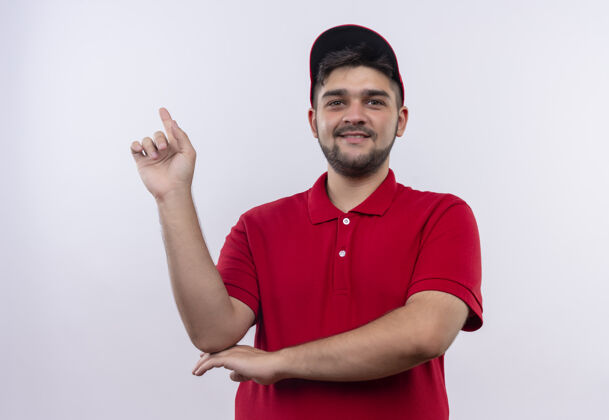 红色身穿红色制服 头戴鸭舌帽的年轻送货员微笑自信地展示食指专注于任务制服立场年轻