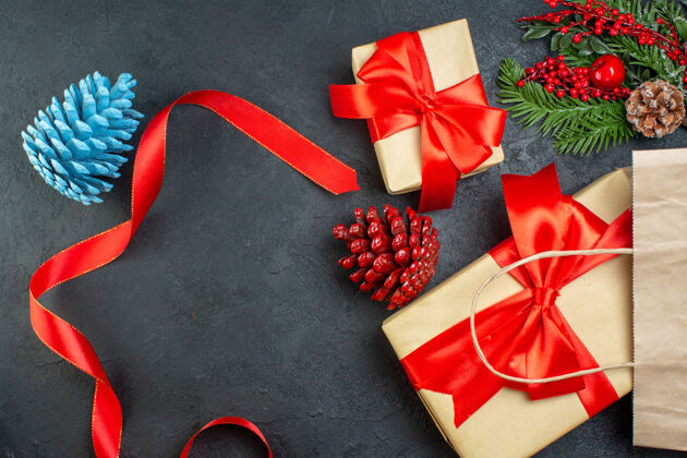 圆锥体一卷红丝带针叶树球果和礼物冷杉树枝在黑暗的桌子上的水平视图红丝带圣诞节轮子