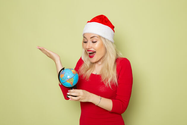 圣诞节正面图美丽的女性手持地球仪在绿墙假日圣诞节地球仪微笑小