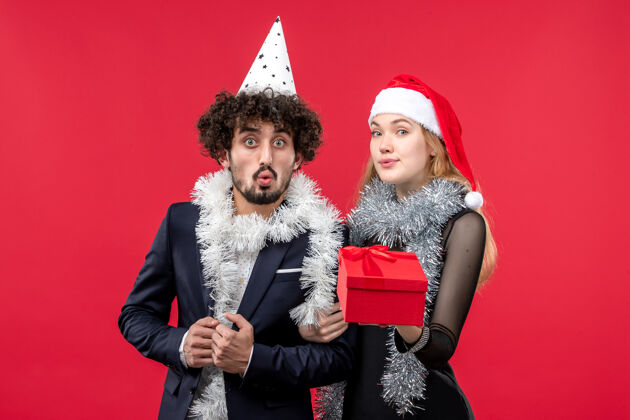 帽子正面图：红地板上的年轻夫妇带着新年礼物圣诞爱情假期圣诞节肖像风景