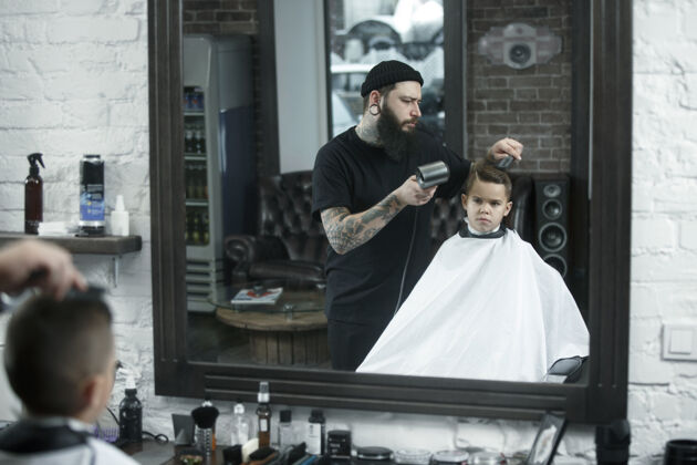 客户儿童理发师在黑暗中剪小男孩发型师男理发