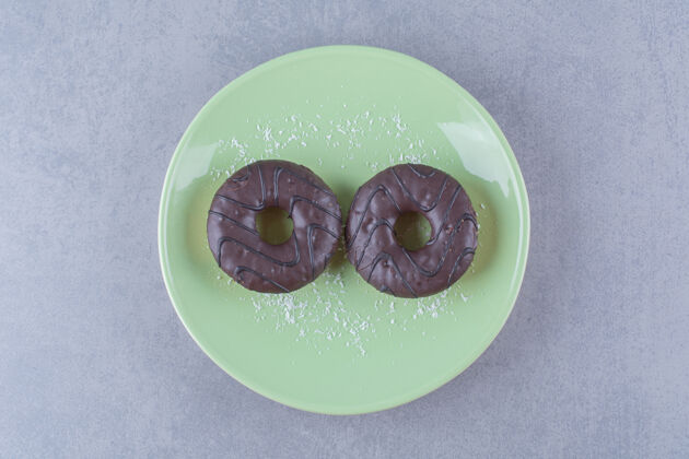 甜甜圈两个新鲜巧克力甜甜圈加糖粉的绿色盘子糖盘子烘焙