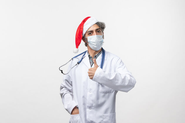 冠状病毒正面图男医生戴着无菌口罩上白墙病毒新年大流行制服圣诞节病毒