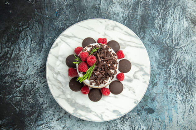 浆果顶视图芝士蛋糕与巧克力在白色椭圆形盘子上的灰色表面自由空间巧克力芝士蛋糕顶部视图
