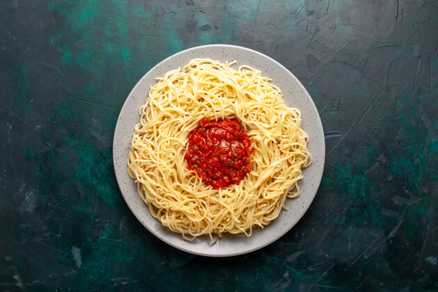 意大利面俯视图：深蓝色表面上有肉末和番茄酱的熟意大利面食顶部烹饪意大利面酱汁