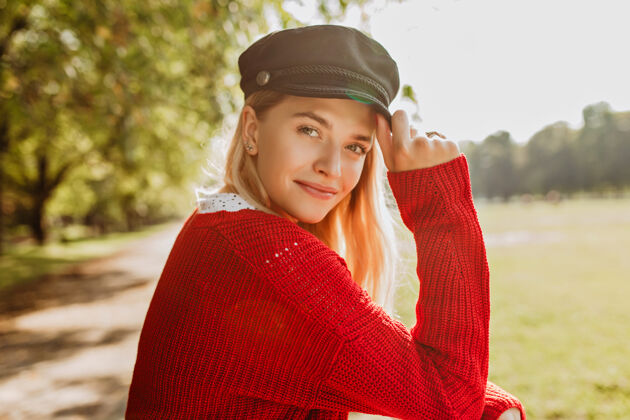 肖像美丽的金发美女穿着红色套头衫 戴着时髦的黑帽子站在公园里微笑的女孩享受阳光明媚的秋日金发优雅漂亮