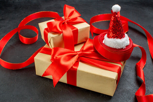 帽子侧视图美丽的礼物与红丝带和圣诞老人帽子在黑暗的背景风车壁板圣诞节