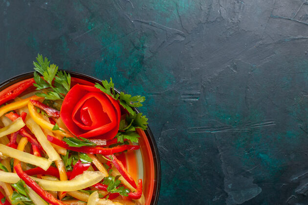 盘子上图：深蓝色的盘子里有切碎的甜椒和不同颜色的蔬菜沙拉铃铛深蓝色花