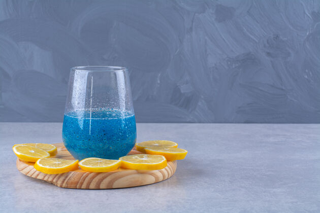 异国情调把柠檬片放在一杯蓝色冰沙旁边 放在一个木板上 放在大理石桌上柠檬维生素切片