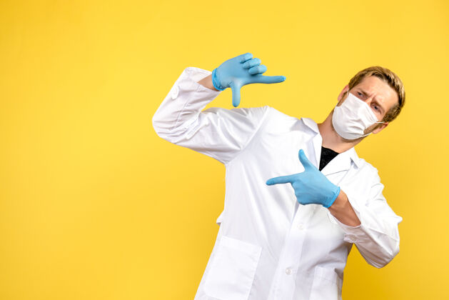 看正面图：黄色背景上的男医生在拍照健康病毒大流行男性男性医生专业