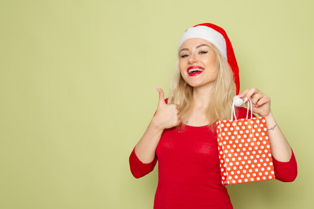 肖像正面图漂亮的女人拿着礼物在绿色的墙上小包装圣诞雪颜色新年情感包装漂亮情感