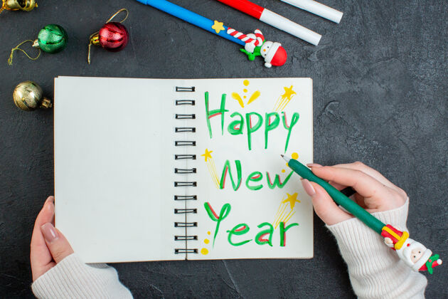 钢笔手握钢笔的螺旋笔记本俯视图 黑色桌子上有新年快乐书写装饰配件笔记本螺旋笔记本教育