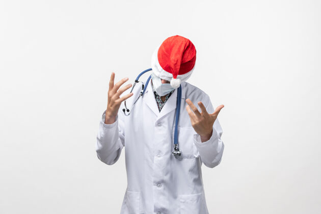 圣诞节正面图：戴着红帽子的男医生在白墙上新年病毒大流行微笑男医生帽子