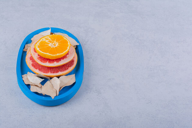 切片新鲜的葡萄柚 柠檬和橙色的戒指放在蓝色的盘子里新鲜柑橘葡萄柚
