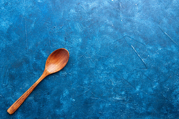 晚餐蓝色地面上的木勺顶视图 有复印空间地厨房木头勺子