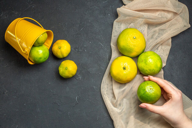 柠檬顶视图新鲜柠檬米色薄纱披肩柠檬从桶柠檬分散在女性手中黑暗的表面柑橘顶部关键酸橙