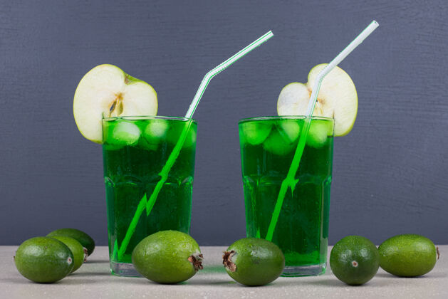 提神两杯绿色果汁 蓝色墙上有吸管水果成熟饮料