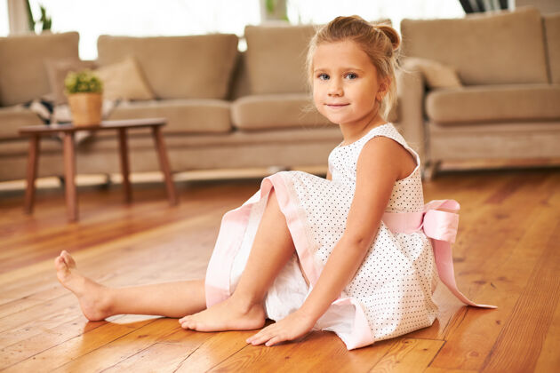 衣服美丽迷人的小女孩穿着喜庆的裙子 光着脚坐在厨房的地板上童年漂亮公主