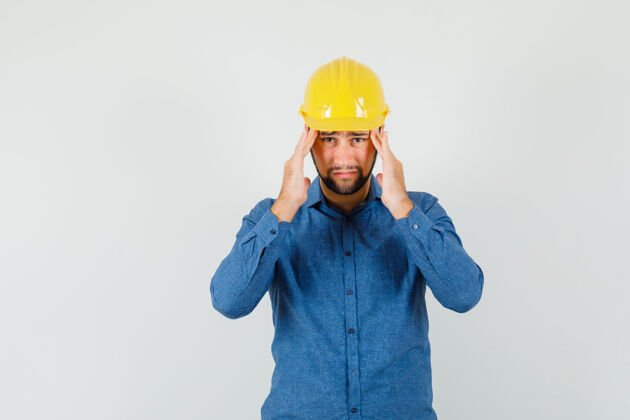 工程师一个年轻工人穿着衬衫 戴着头盔 头痛得厉害 看上去很累头痛强大专业