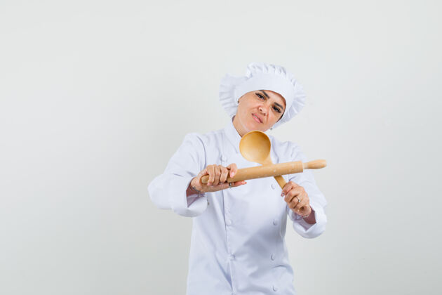 制服穿着白色制服的女厨师手拿擀面杖和木勺 看上去很自信专业帽子柜台