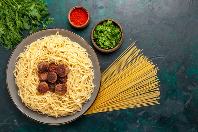 烹饪俯视图煮熟的意大利面食 深蓝色表面有肉丸和绿色菜肴面团绿色