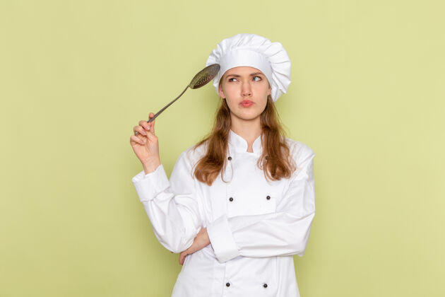 银身着白色厨师服的女厨师手持大银勺站在绿色墙上思考衣服食物护士