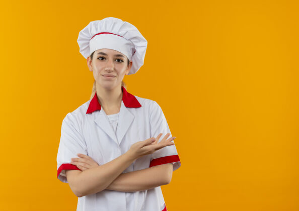 请年轻漂亮的厨师穿着厨师制服 站在那里 闭着身子 空荡荡的手孤立在橙色的空间里空制服站