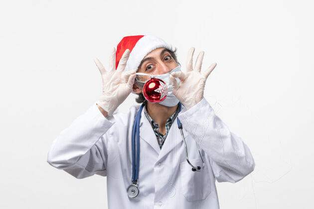 听诊器正面图男医生手持新年树玩具健康冠状病毒肖像冠状病毒实验室外套