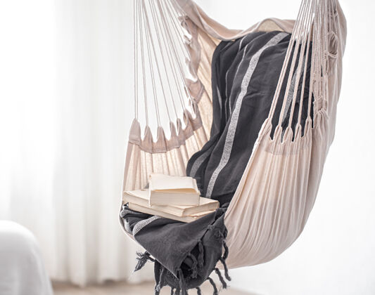 地方波西米亚风格的吊床椅和一堆书这是一个在家放松的舒适的地方舒适椅子休息