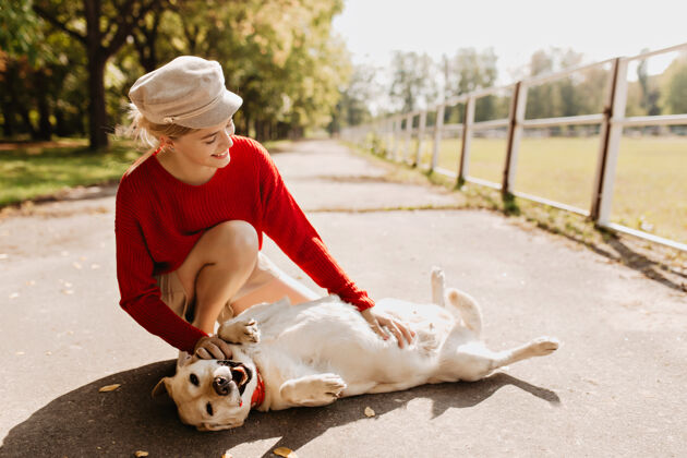 漂亮美丽的女孩和她的狗一起在公园里玩耍时髦的金发女郎和她的宠物在秋天的阳光下放松游戏宠物长发