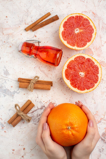 瓶子俯视切割柚子肉桂棒瓶柚子在女性手裸体表面维生素甜橙果汁