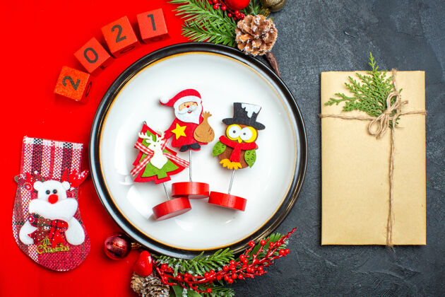 号码餐盘装饰配件的俯视图杉木树枝和数字圣诞袜放在一张红色餐巾旁边的礼物放在一张黑色的桌子上袜子头顶圣诞节