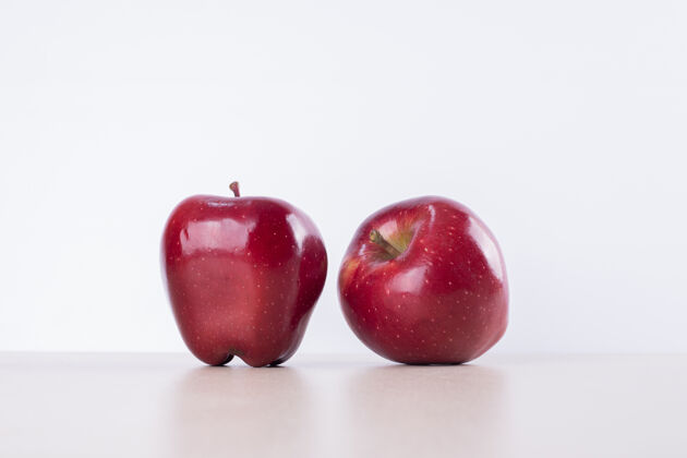 生的两个红苹果在白苹果上美味素食天然