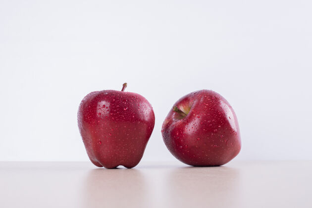 多汁的两个红苹果在白苹果上有机水果美味
