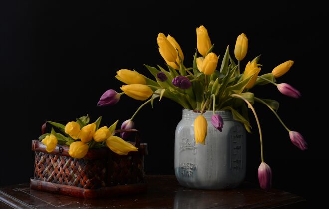自然一束美丽的黄色和紫色郁金香放在棕色桌子上的灰色花瓶里植物花园叶