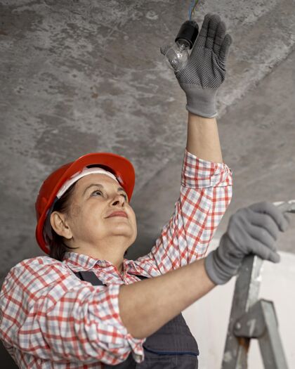 行业戴着头盔和手套的低角度女建筑工人就业安全帽职业