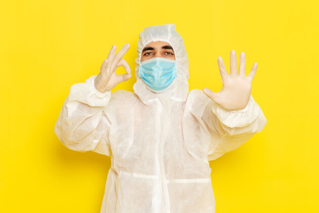 科学身穿特殊防护服 戴着面罩的男性科学工作者的正面图 手掌放在淡黄色的墙上人光危险