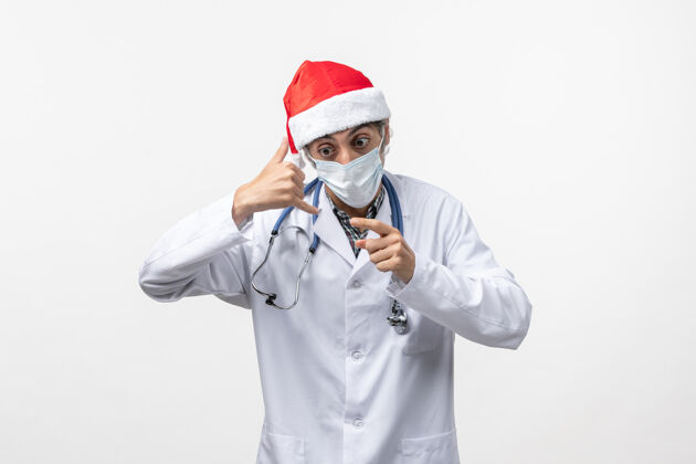 男人正面图白色办公桌上戴口罩的男医生可维假日大流行病毒制服病毒视图