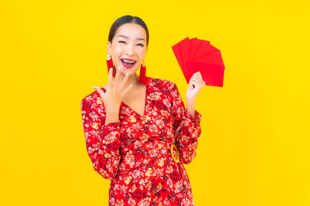 女性在黄色的墙上画一幅美丽的亚洲年轻女子拿着红包手表愿望服饰