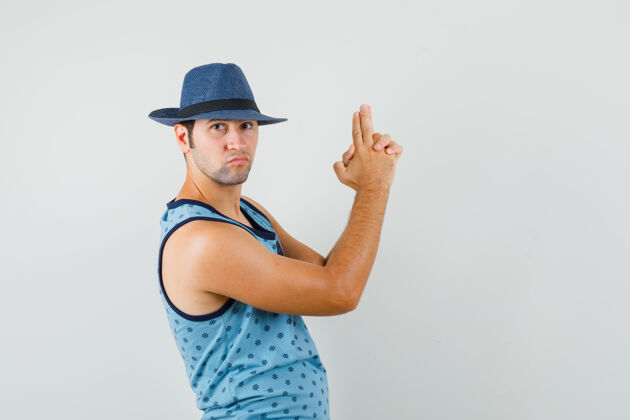成功年轻人做手指标志在蓝色单打 帽子和看起来很自信胡须友好