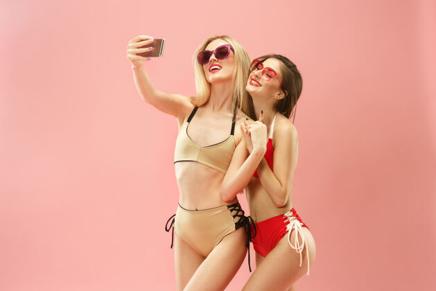 欢呼穿着泳装的可爱女孩在摄影棚摆姿势 用手机自拍粉色的夏日写真高加索青少年自拍女性漂亮