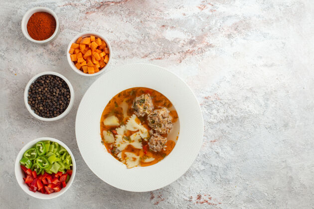 蔬菜顶视图肉汤美味的汤与切片蔬菜和不同的调味料在白色背景菜餐肉