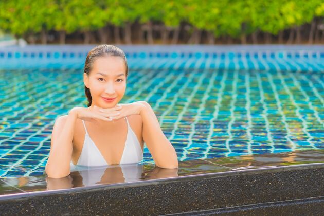水肖像美丽的亚洲年轻女子放松微笑休闲围绕室外游泳池近海度假旅游女人