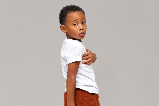 头发一个穿着白色t恤的困惑的黑皮肤男孩的孤立肖像英俊的非洲孩子摆姿势肢体语言非洲孩子随意