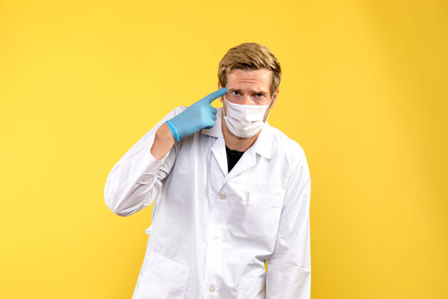男性正面图男性医生在看黄色背景的健康病毒大流行病毒成人衣服