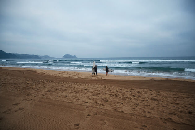 波浪两个面目全非的冲浪女孩带着她们的长板 一大早就呆在海边看海浪 穿着湿衣 准备冲浪二十岁人私人教练