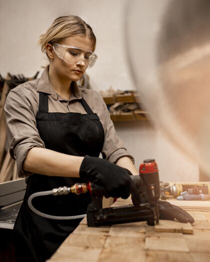 女性侧视图的女木匠与气动订书机在工作室技能女人工作