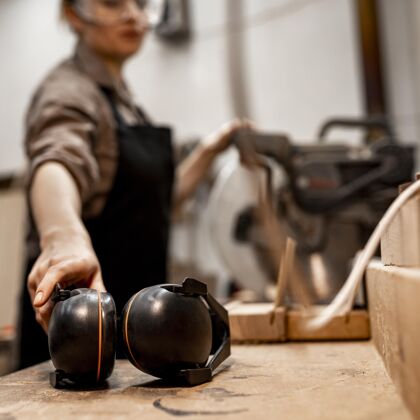工人女木匠在工作室里戴着耳机妇女女性职业